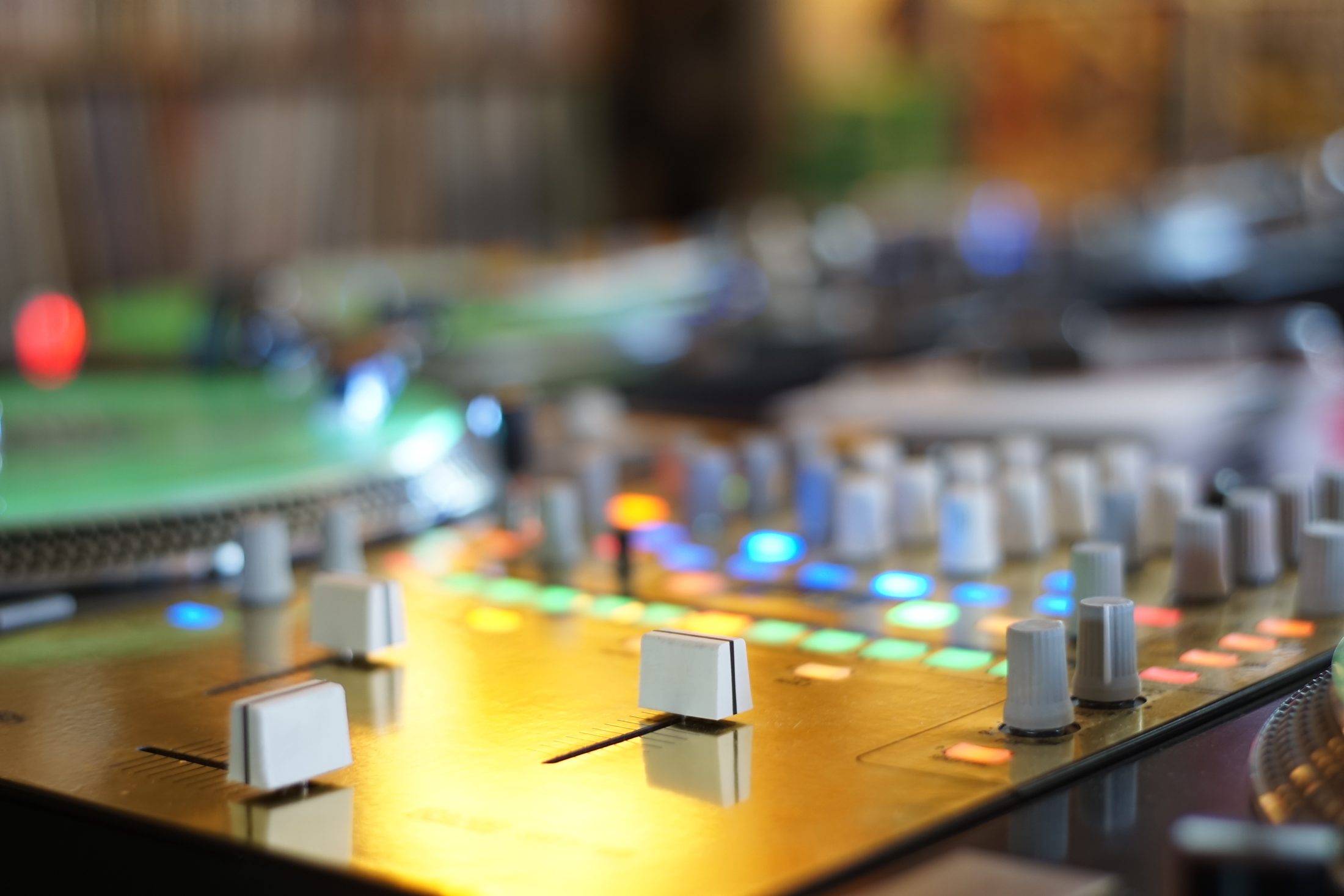 Close-up of a gold DJ mixer with lit pads and faders