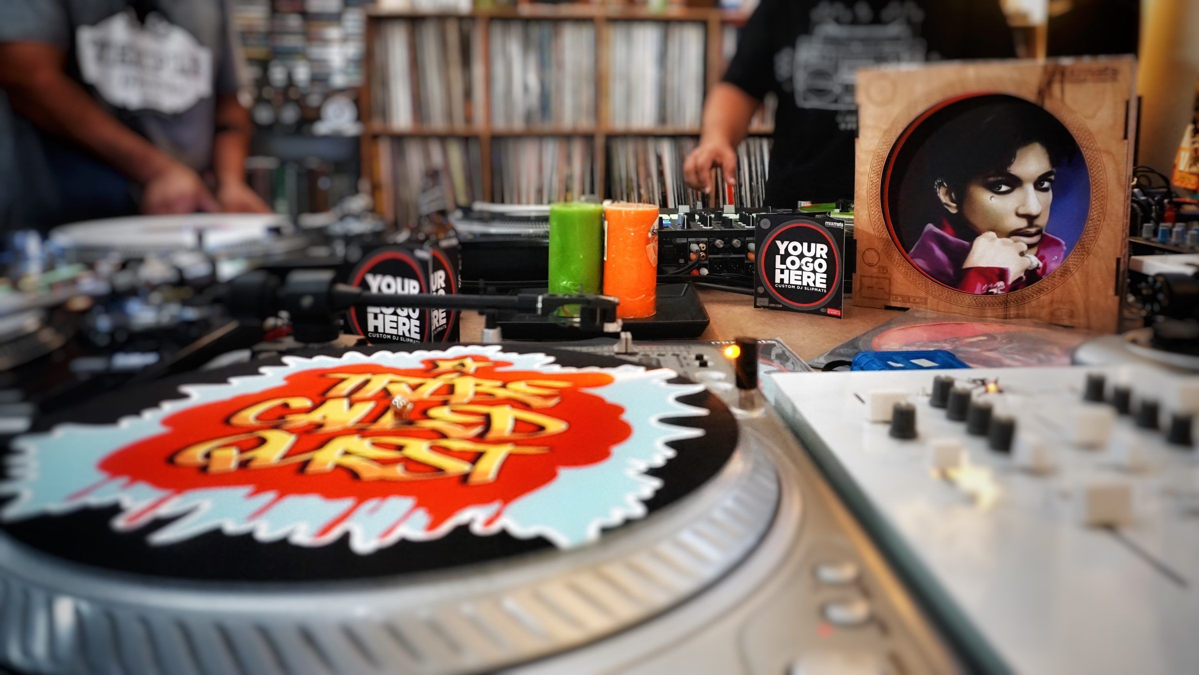Custom Mixmats slipmats on turntables in a record store, with DJs mixing behind the decks